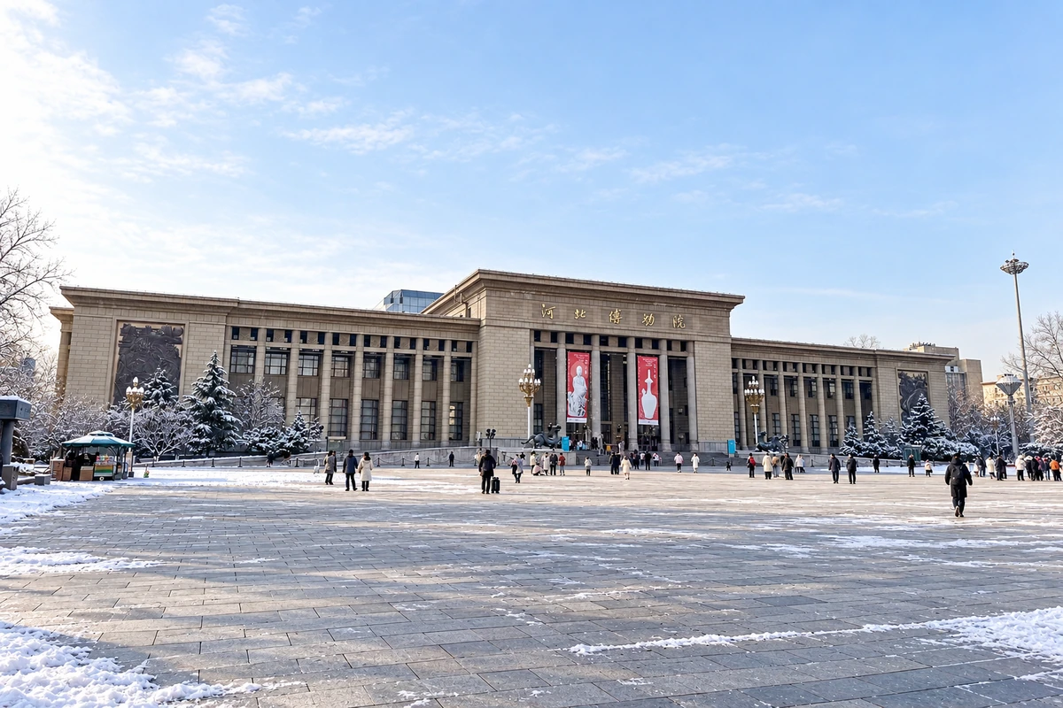 薄雪和冷色晨光衬托北区柱列与浅色墙面，广场延续入口轴线；雪景为 AI 视觉演绎。
