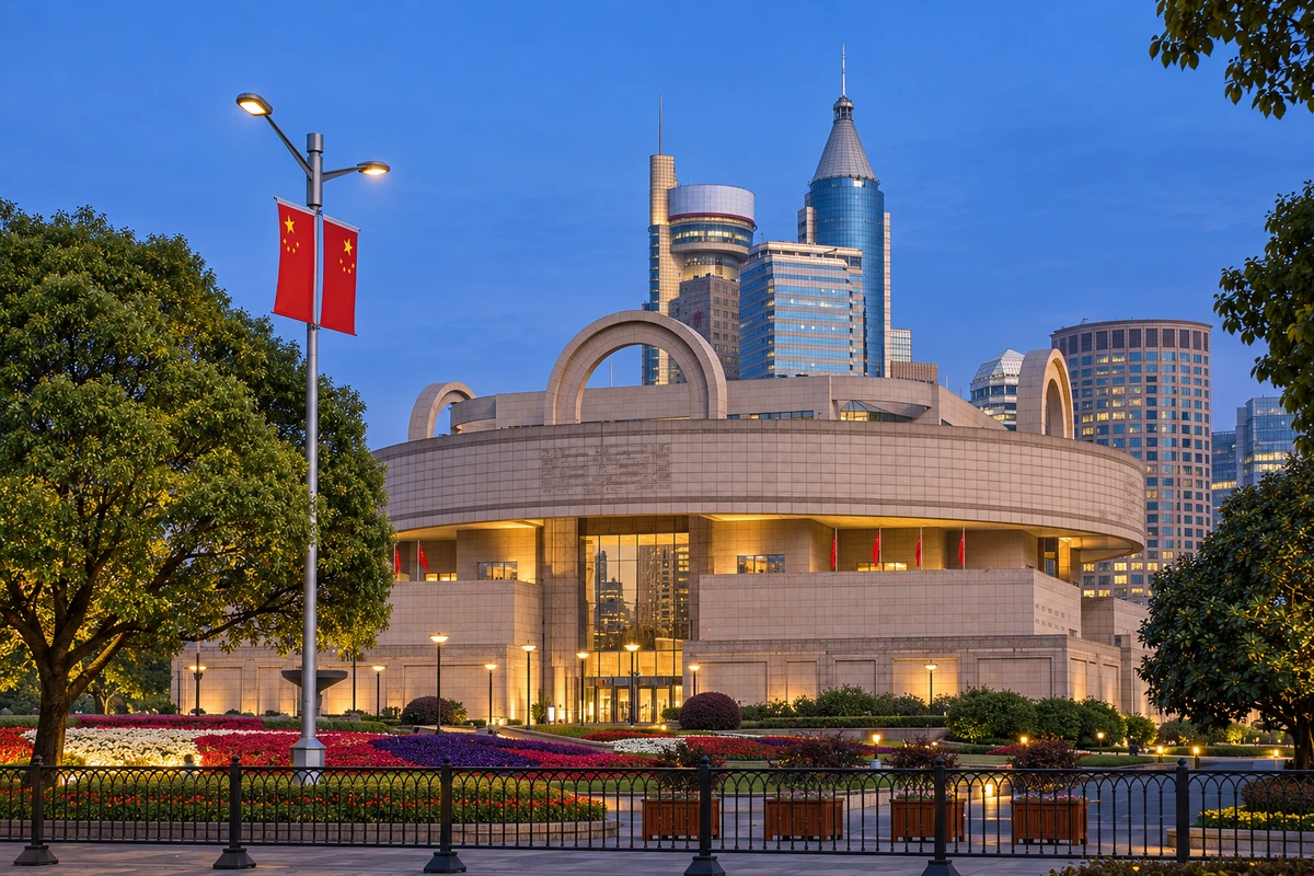 AI 视觉演绎：城市暮光里的圆鼎。蓝调时刻的馆舍保留清晰弧线，暖色入口与周围城市灯光互相回应。季节与光线为 AI 视觉演绎。
