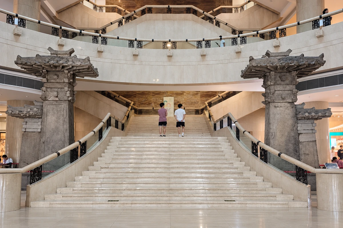 乌杨石阙（历史展陈）：两侧石阙在中庭展陈中形成一组建筑尺度，石材构件与现代台阶呈现不同历史层次。