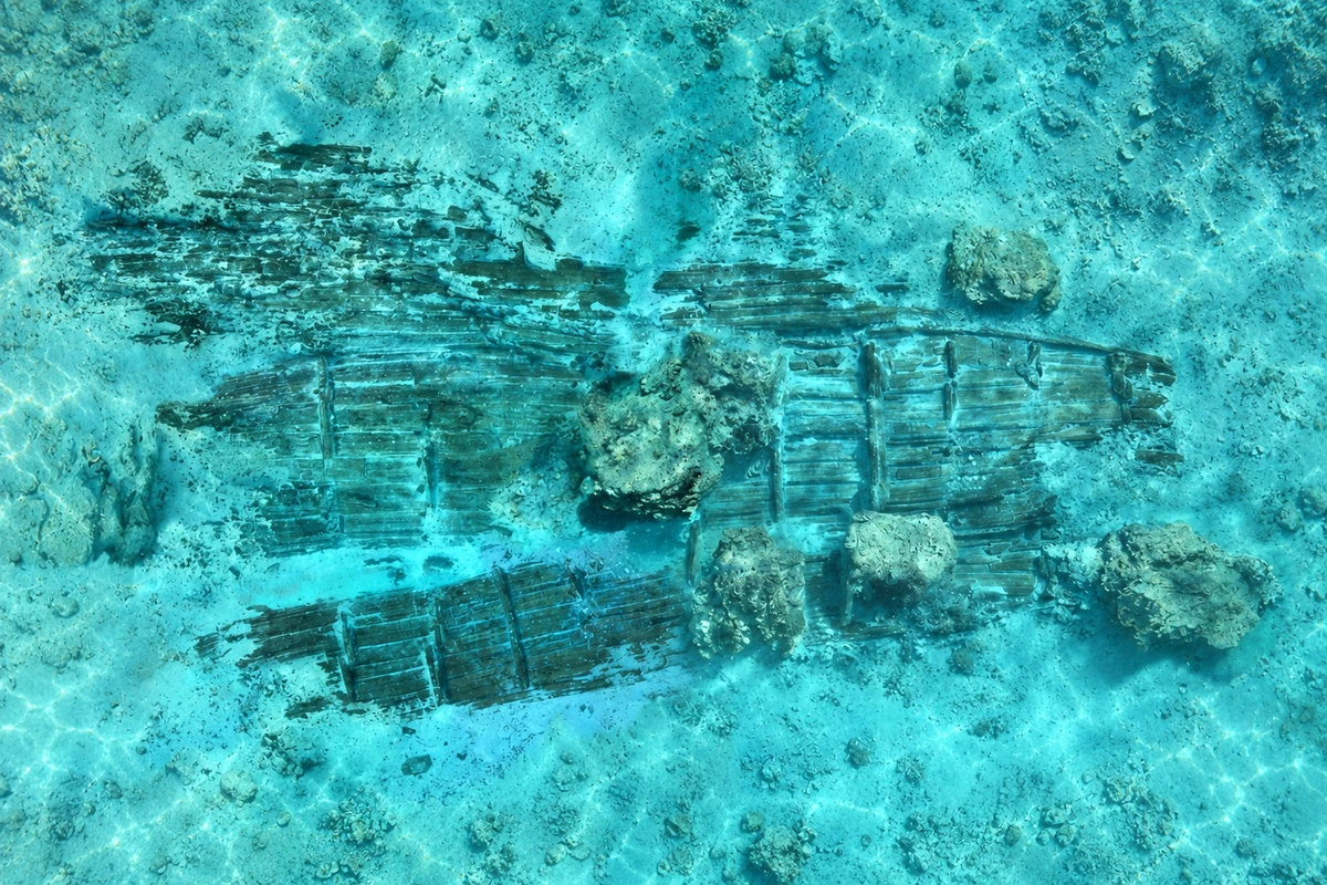 华光礁Ⅰ号沉船残体（水下遗存参考）：海床中的残体以木构轮廓和散落遗物呈现沉船环境，让观看从瓷器回到航行的物质背景。