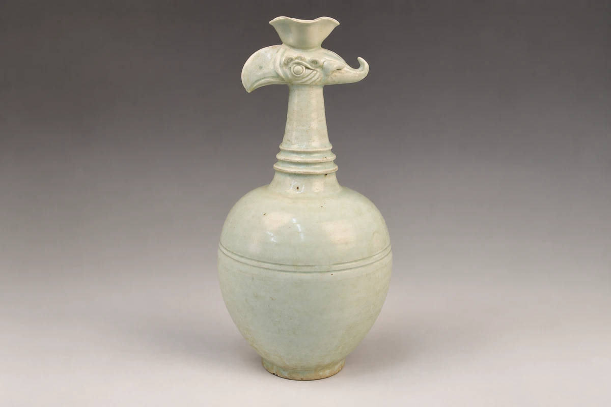 青白釉花口凤首壶：花口、凤首与细长颈部形成鲜明器形，浅釉色让塑造与刻划痕迹保持柔和的层次。