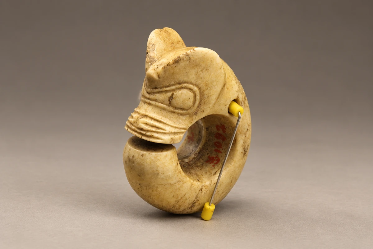 红山文化玉猪龙：开口的环形身体与兽首相接，厚重的玉料在小体量中形成鲜明的轮廓。